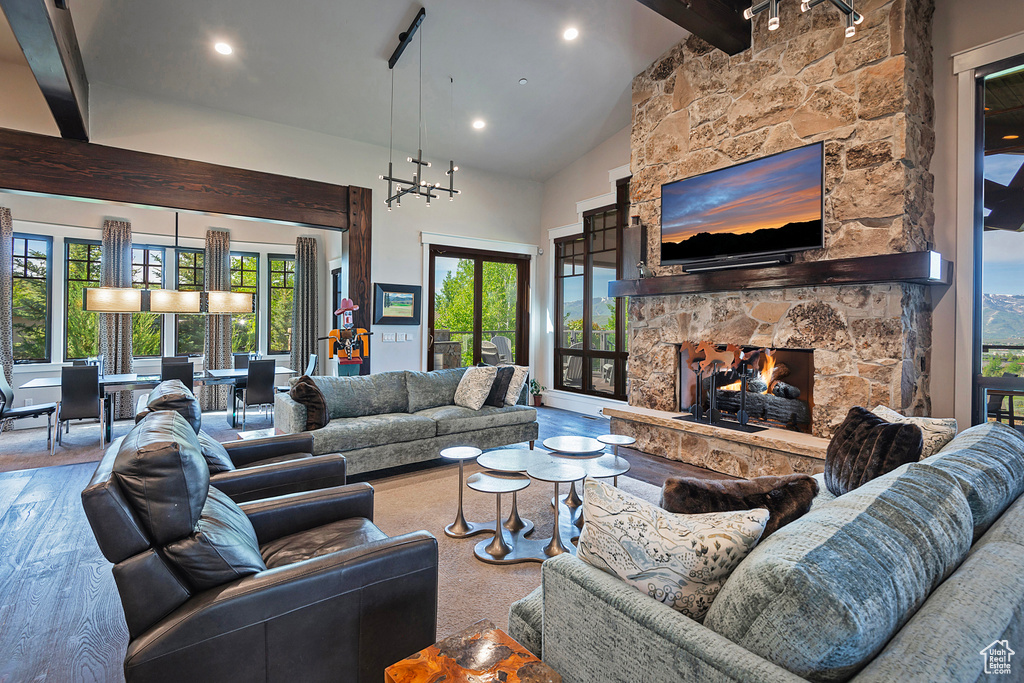 Living room with beamed ceiling, a fireplace, high vaulted ceiling, wood finished floors, and recessed lighting