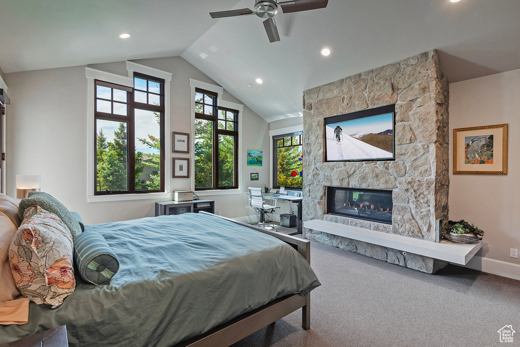 Carpeted bedroom featuring baseboards, a stone fireplace, vaulted ceiling, recessed lighting, and ceiling fan
