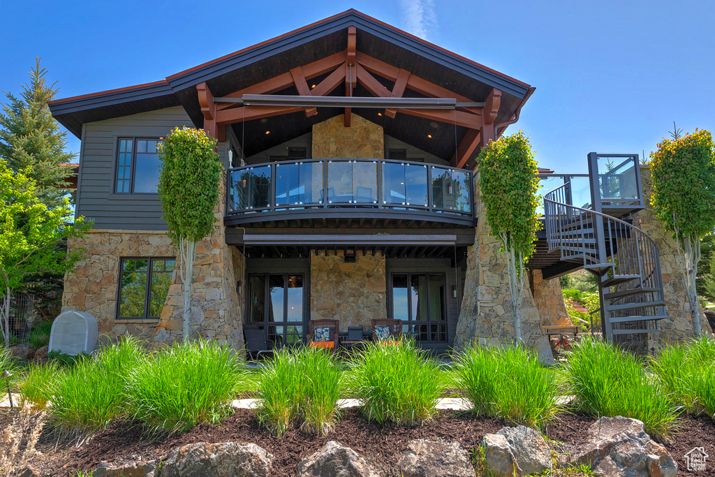 Rear view of property with a balcony, stone siding, and stairway