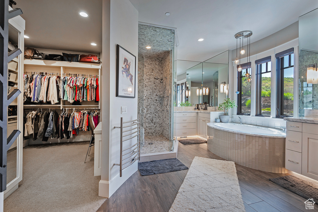 Full bathroom with vanity, a shower stall, a garden tub, wood finished floors, and recessed lighting