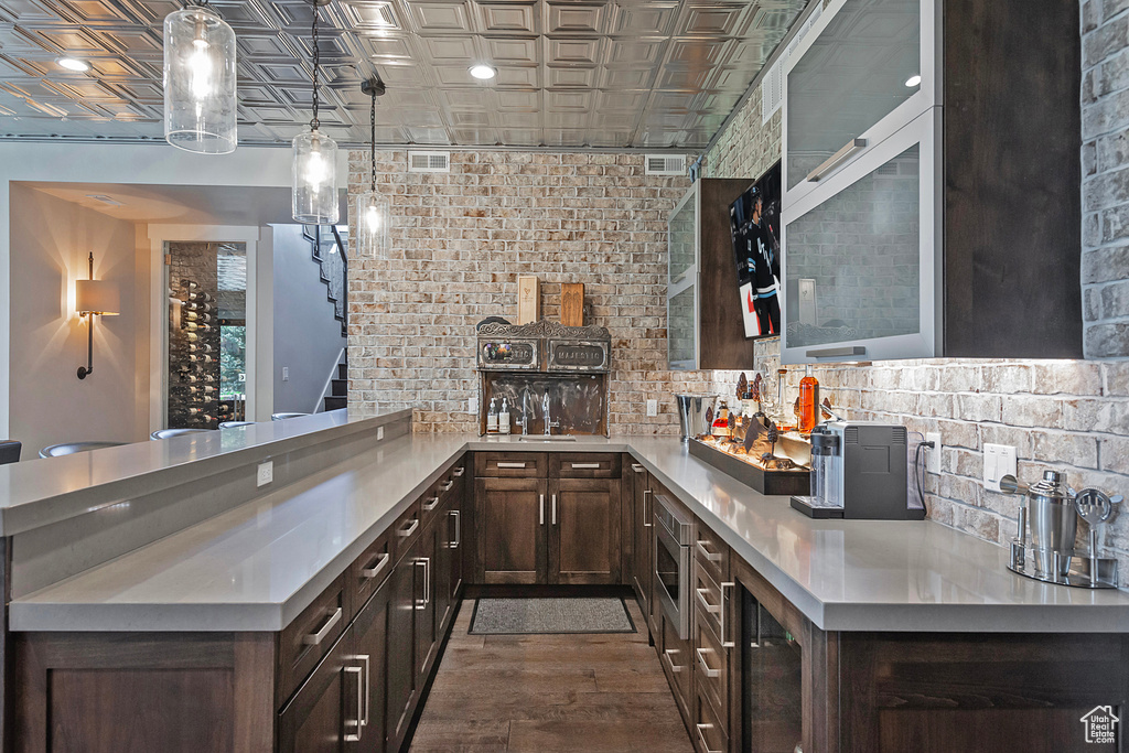 Kitchen with an ornate ceiling, light countertops, backsplash, dark brown cabinets, and dark wood-type flooring