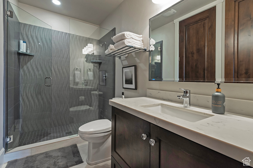 Full bath featuring toilet, vanity, a stall shower, and tile patterned floors