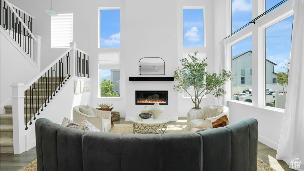 Living room featuring a high ceiling, wood finished floors, stairway, a glass covered fireplace, and baseboards