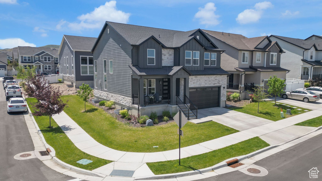 View of front of property with stone siding, a residential view, an attached garage, and board and batten siding