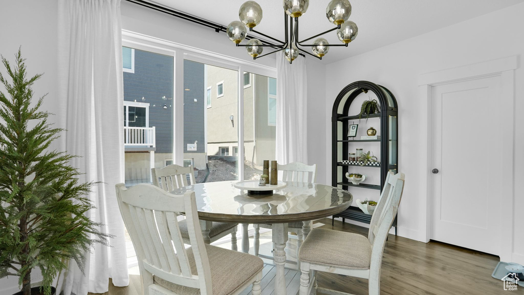Dining area with a chandelier, wood finished floors, and healthy amount of natural light