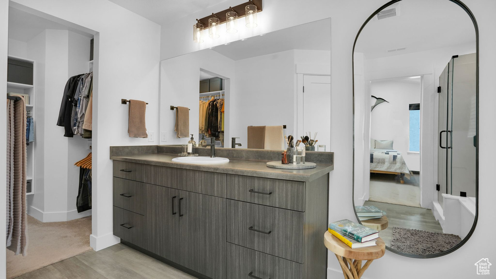 Bathroom with vanity, wood finished floors, a spacious closet, and baseboards