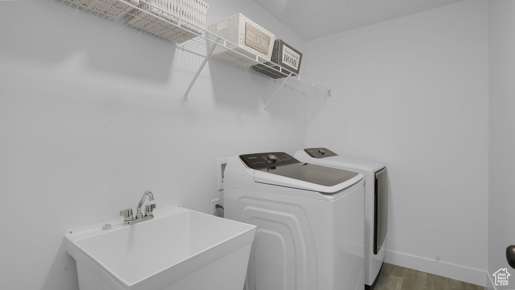 Laundry room with washing machine and dryer, wood finished floors, and baseboards