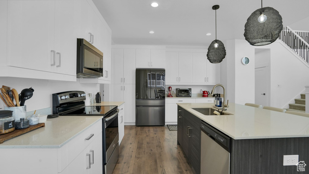 Kitchen with appliances with stainless steel finishes, a sink, light countertops, hanging light fixtures, and recessed lighting
