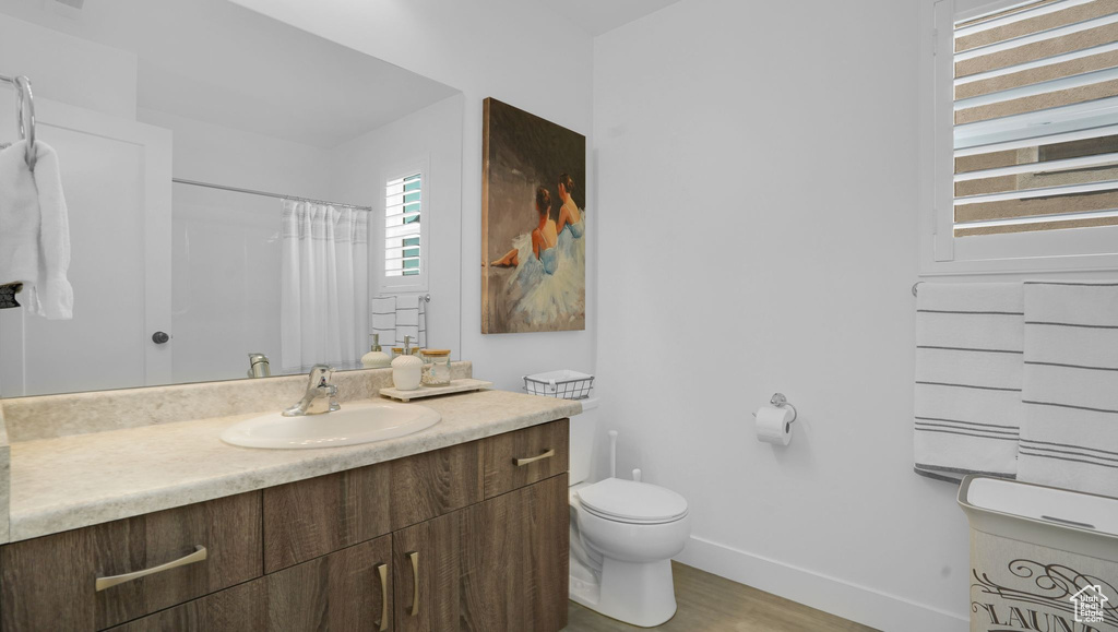 Bathroom featuring vanity, baseboards, toilet, wood finished floors, and a shower with curtain