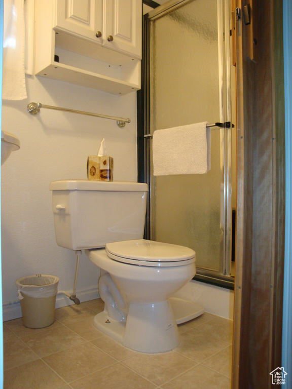 Bathroom featuring a shower stall, toilet, tile patterned flooring, and baseboards