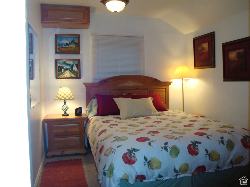Bedroom featuring vaulted ceiling, baseboards, and wood finished floors