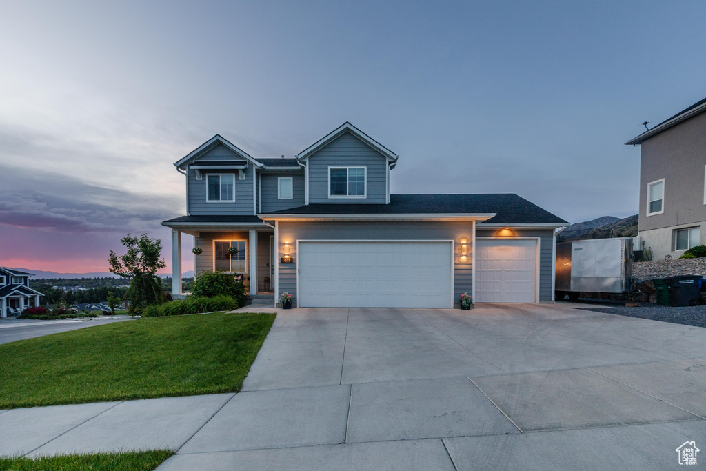 View of front of home featuring driveway, a lawn, and an attached garage