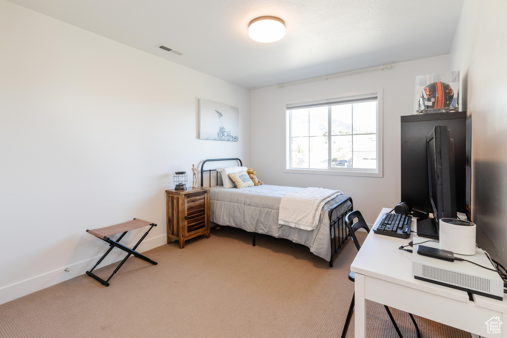Bedroom with light carpet, baseboards, and an office area