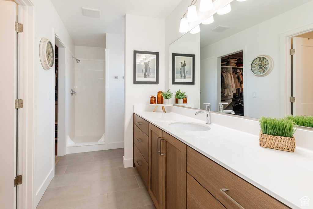 Full bathroom with vanity, a stall shower, a walk in closet, and baseboards