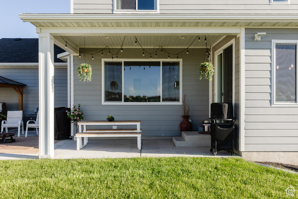 Doorway to property with a patio and a lawn