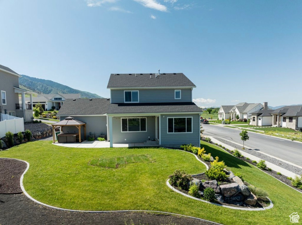 Back of house with a gazebo, a patio, a residential view, and a mountain view