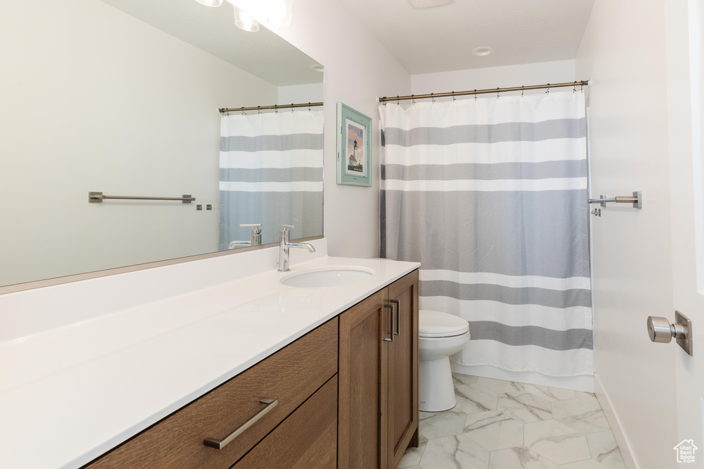 Bathroom with marble look tile flooring, vanity, toilet, baseboards, and a shower with curtain