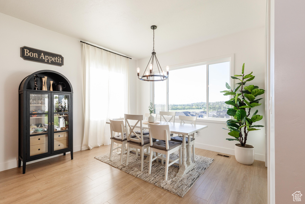 Dining room featuring a chandelier, light wood-type flooring, and baseboards