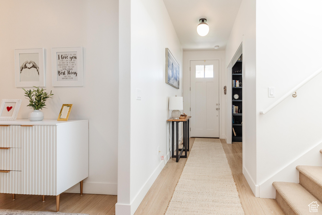 Foyer with light wood finished floors, stairs, and baseboards