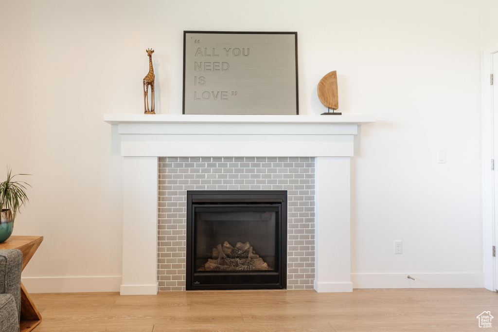 Detailed view of a glass covered fireplace, baseboards, and wood finished floors