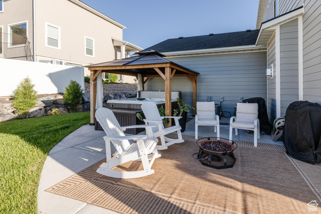 View of patio with a hot tub, an outdoor fire pit, a gazebo, and a grill