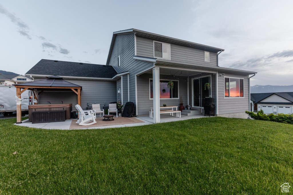 Rear view of house with a patio, a lawn, and a gazebo