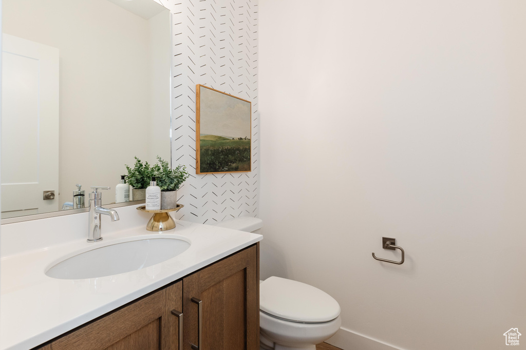 Bathroom with toilet, vanity, and baseboards