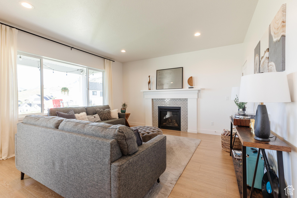 Living area featuring light wood-style flooring, recessed lighting, a brick fireplace, and baseboards