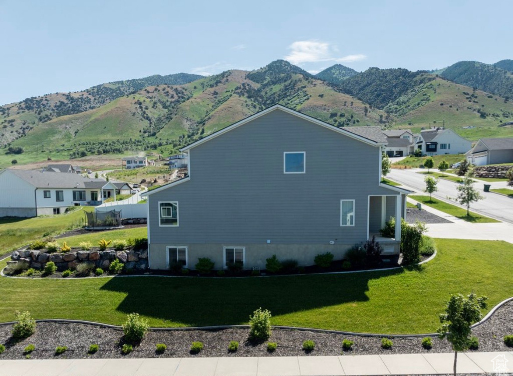 View of home's exterior with a mountain view, a yard, and a residential view