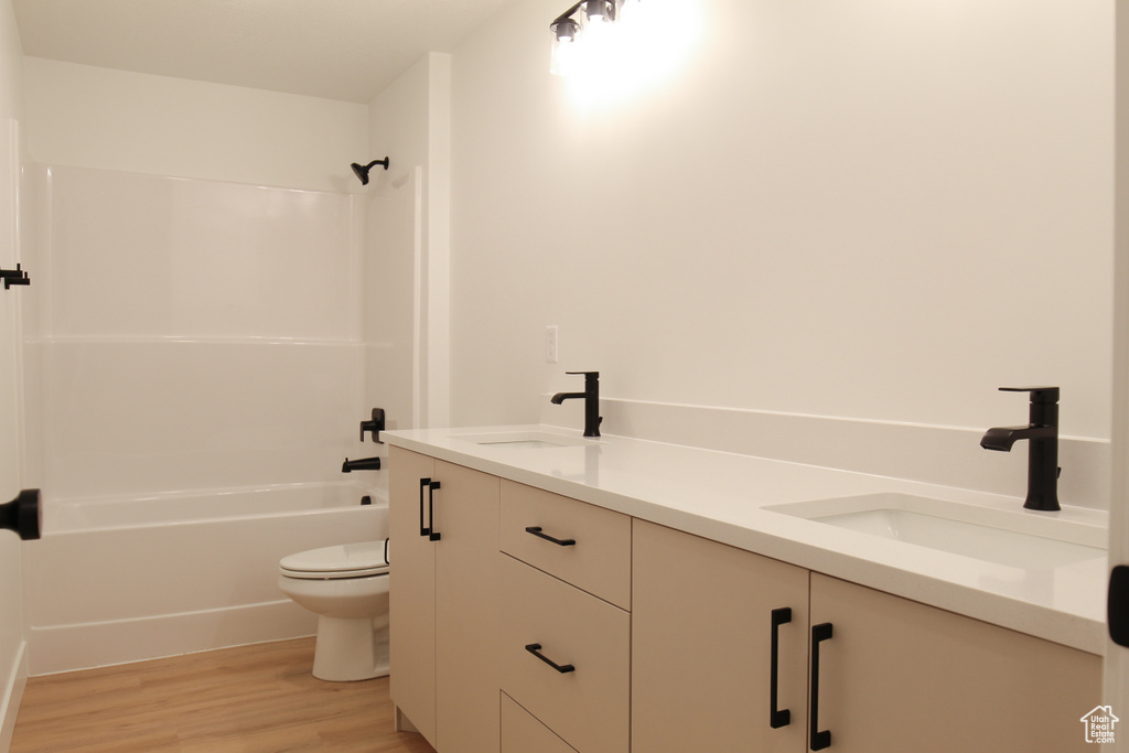 Full bathroom featuring double vanity, wood finished floors, shower / tub combination, and toilet