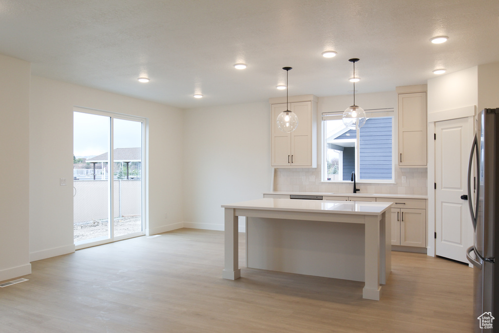 Kitchen with freestanding refrigerator, baseboards, backsplash, light wood-type flooring, and recessed lighting