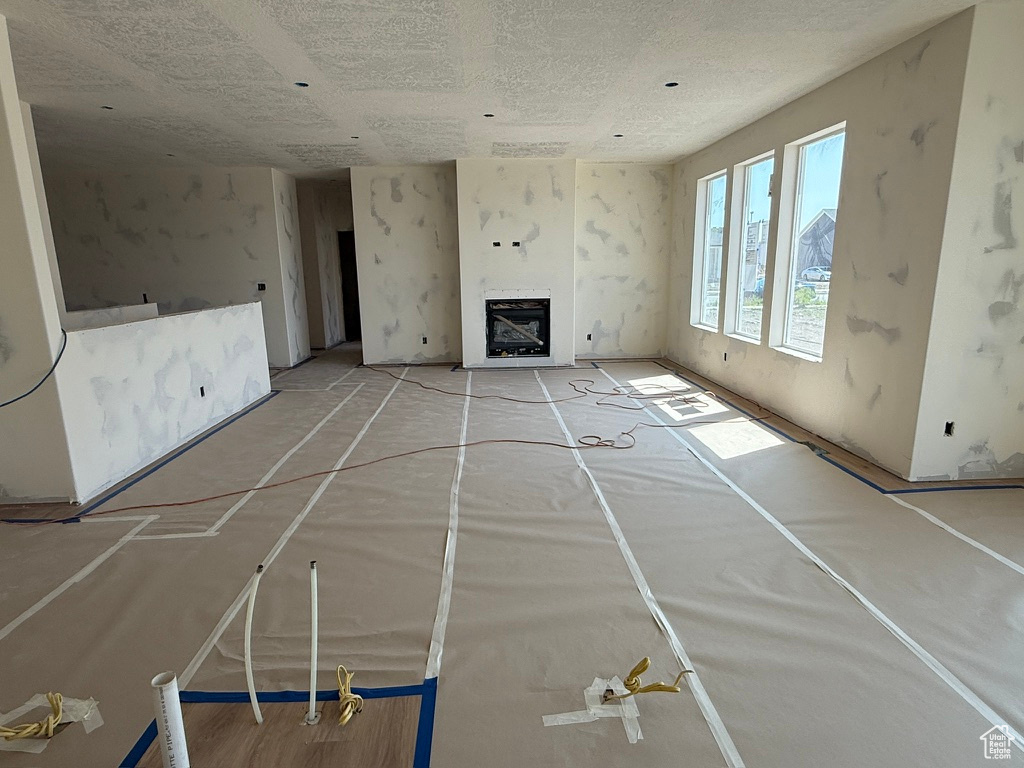 Unfurnished living room featuring a fireplace, heating unit, and a textured ceiling