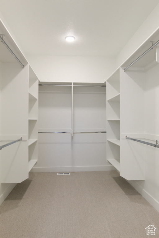 Walk in closet featuring light colored carpet
