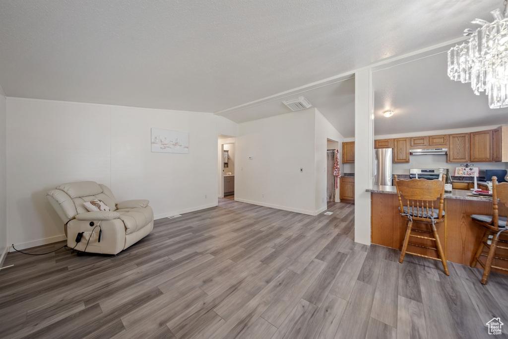 Kitchen featuring freestanding refrigerator, open floor plan, brown cabinets, light wood-style flooring, and a breakfast bar area