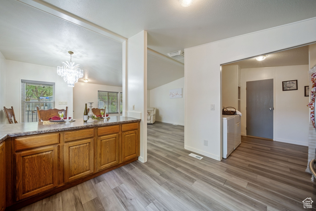Bathroom featuring washing machine and clothes dryer, a chandelier, wood finished floors, and vanity