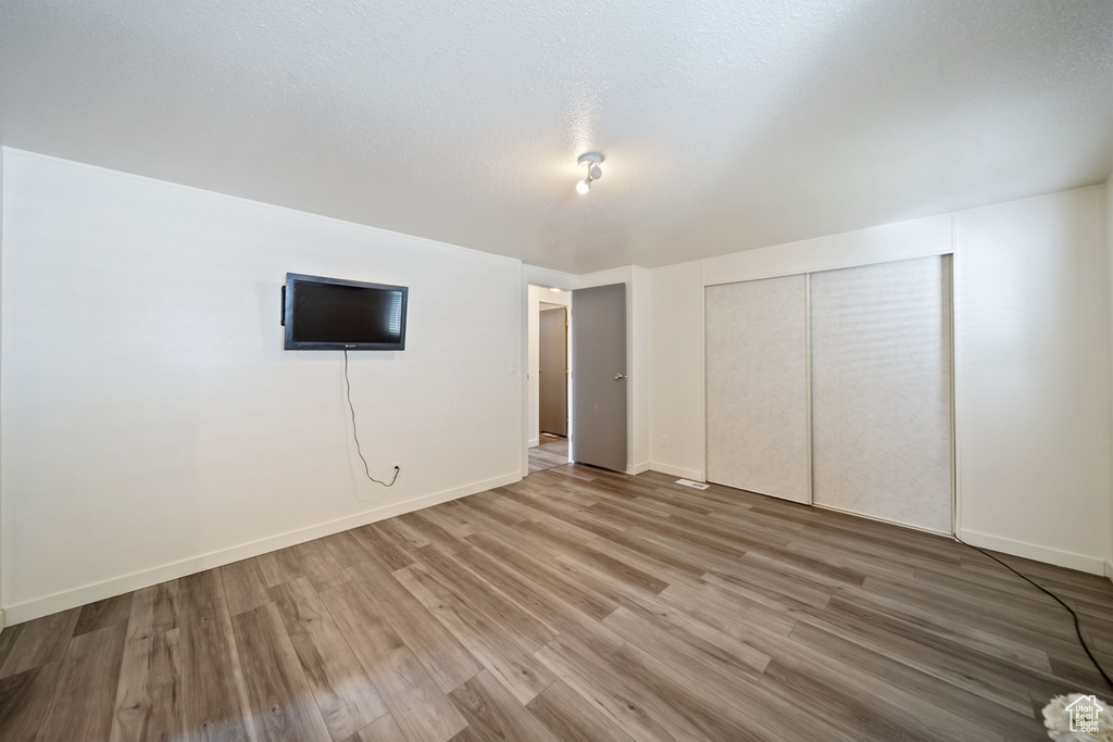 Unfurnished bedroom with light wood-style floors, a closet, and baseboards