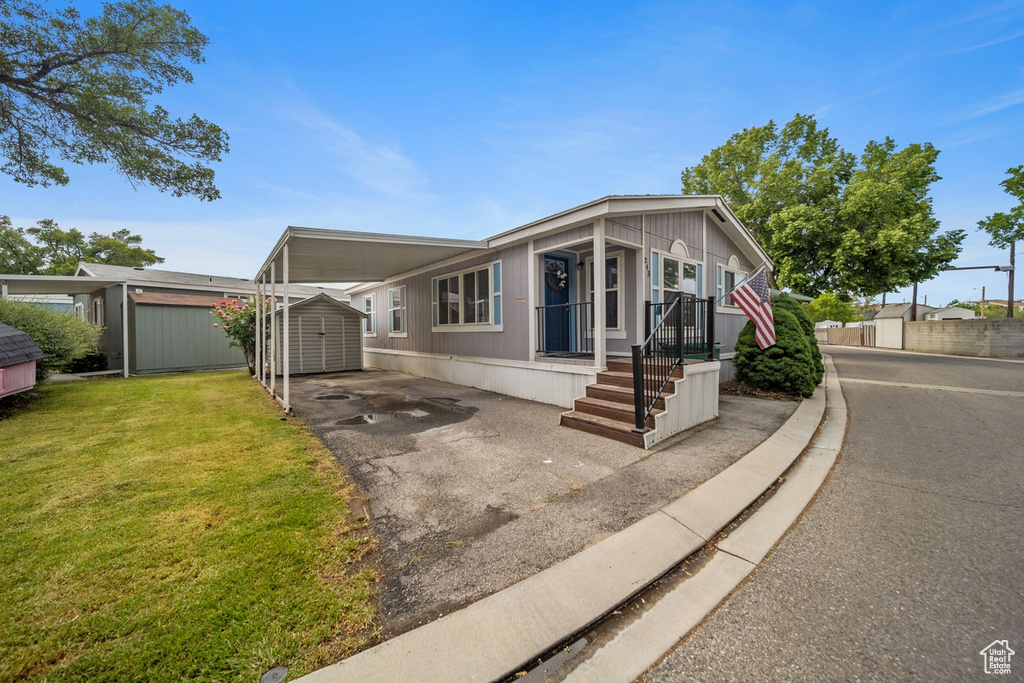 Manufactured / mobile home with driveway, a front lawn, and a carport