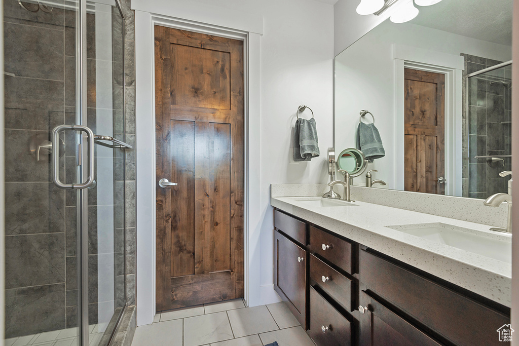 Bathroom featuring double vanity, tile patterned floors, and a stall shower