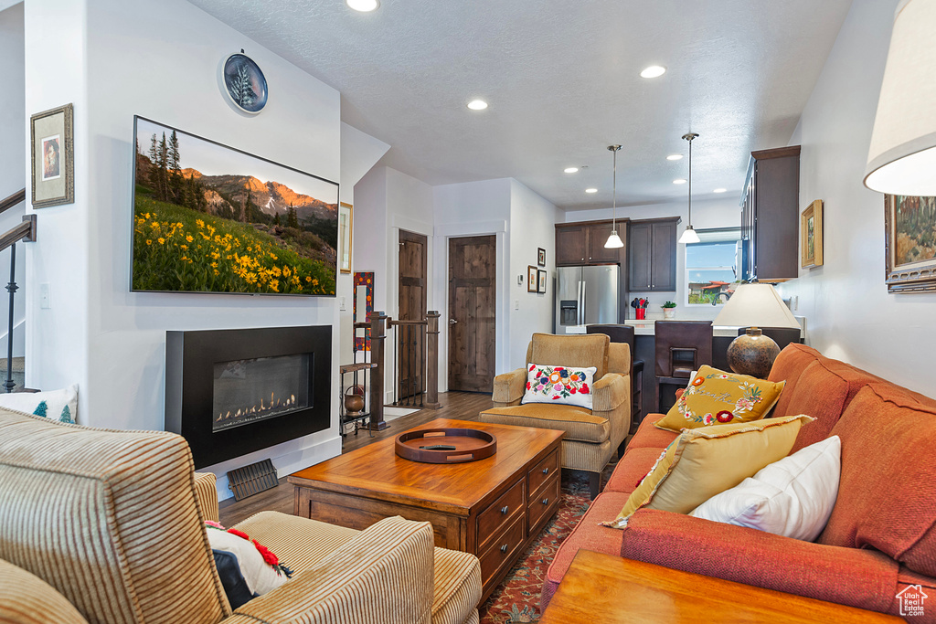 Living area featuring recessed lighting, a glass covered fireplace, and wood finished floors
