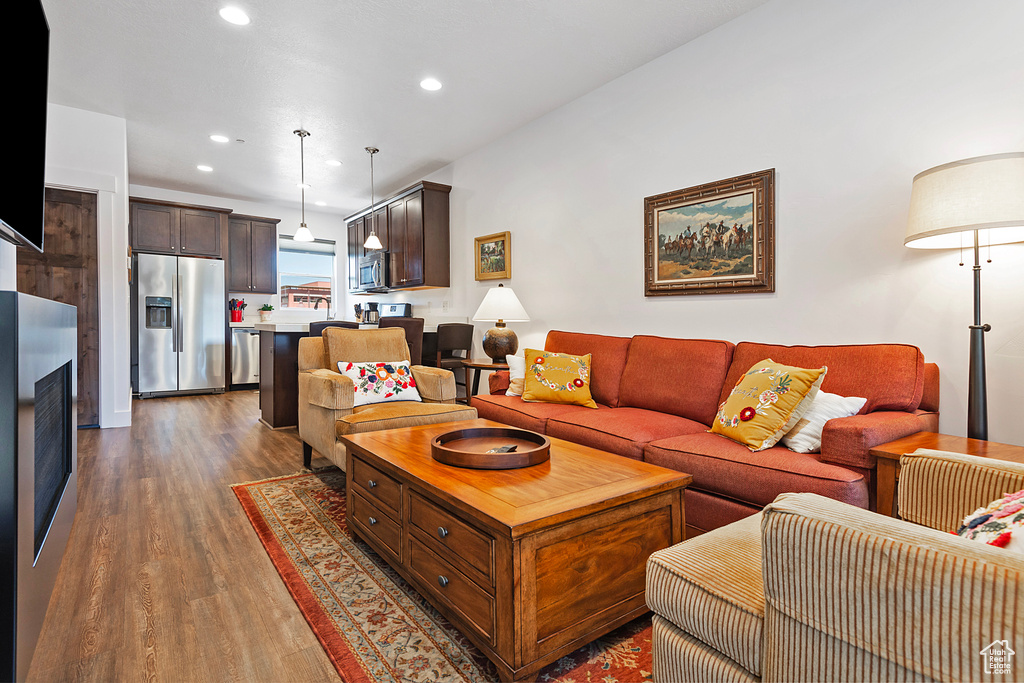 Living room with wood finished floors, recessed lighting, and a fireplace