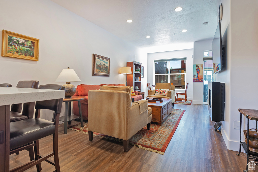Living area featuring recessed lighting, dark wood-style floors, baseboards, and a textured ceiling