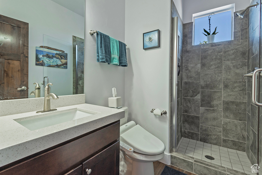 Full bath with toilet, a stall shower, and vanity
