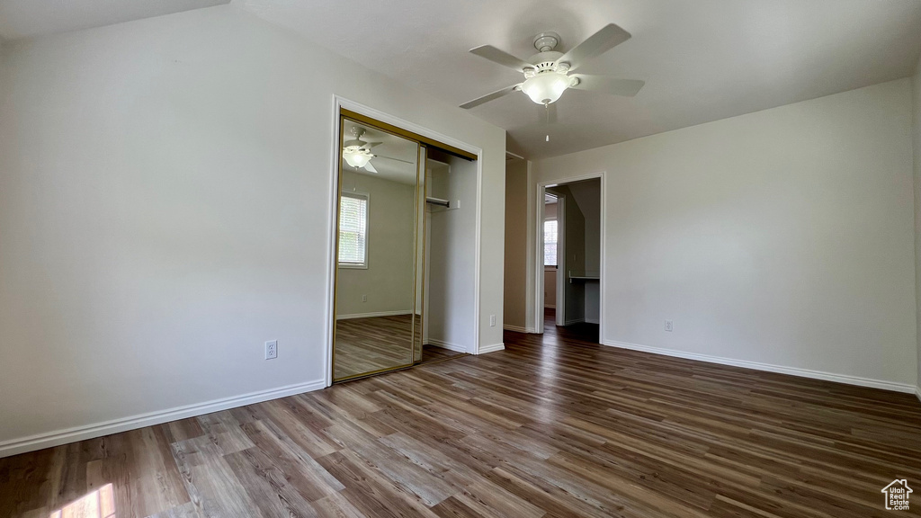 Unfurnished bedroom featuring wood finished floors, baseboards, a closet, and a ceiling fan