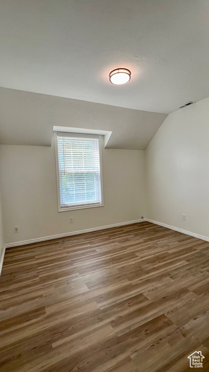 Bonus room with lofted ceiling, wood finished floors, and baseboards