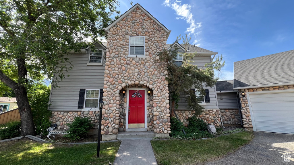 View of front facade featuring stone siding, an attached garage, and asphalt driveway