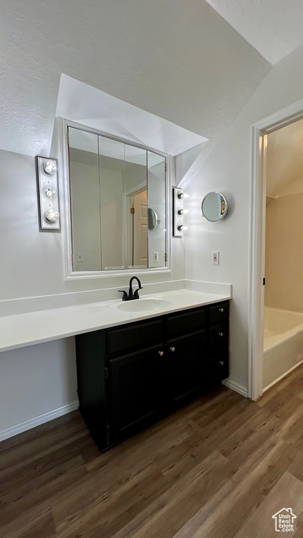 Bathroom with vanity, wood finished floors, lofted ceiling, and baseboards