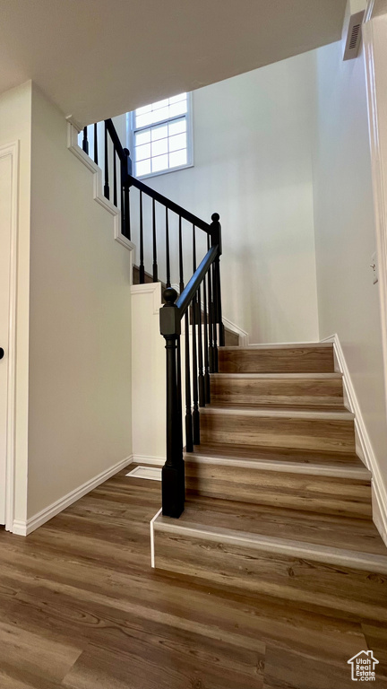Stairway with wood finished floors and baseboards