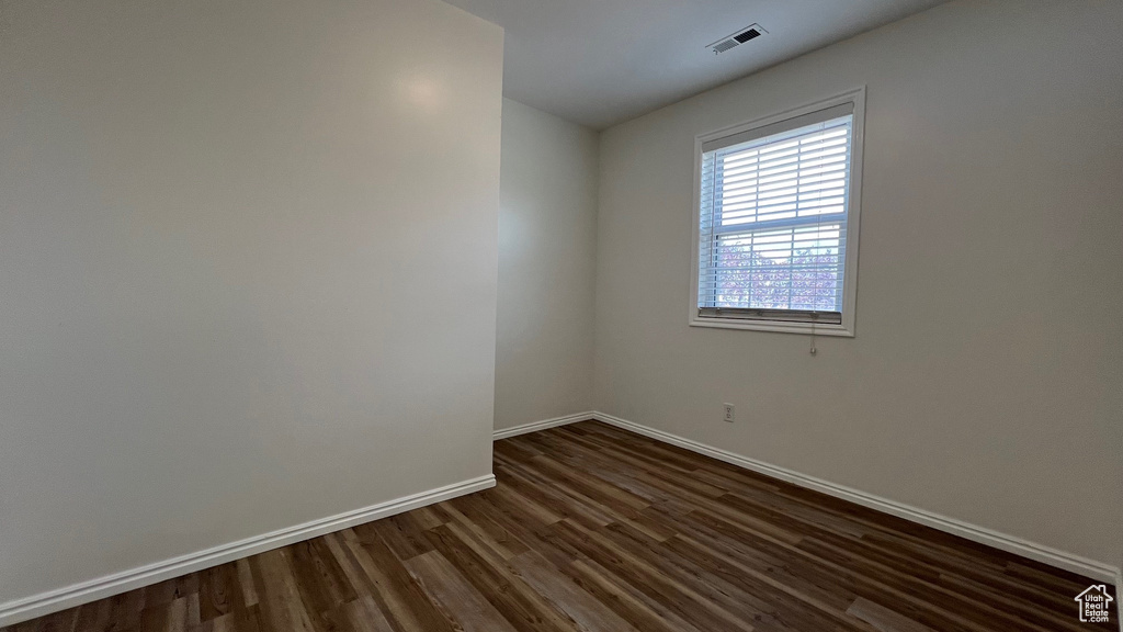 Unfurnished room with dark wood-type flooring and baseboards