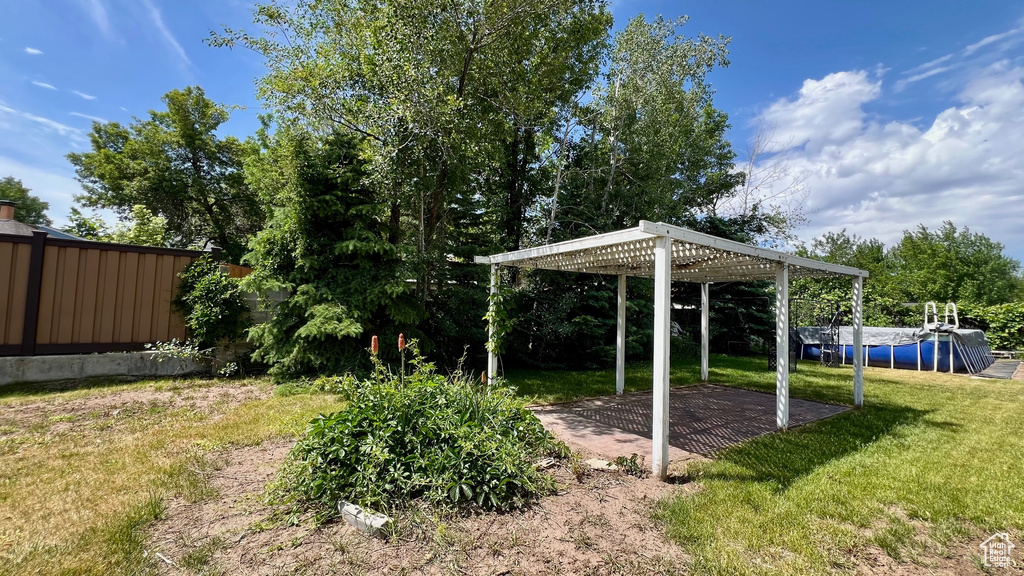 View of grassy yard with a pergola and a patio area