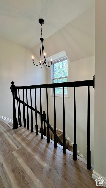 Staircase featuring a chandelier, wood finished floors, and baseboards